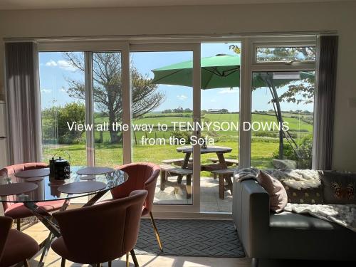 VALLEY VIEW self-catering coastal bungalow in rural West Wight في فريشووتر: غرفة مع طاولة وكراسي ونافذة كبيرة