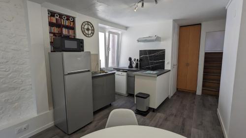 uma pequena cozinha com frigorífico e micro-ondas em L'Entracte - Appart Hôtel - Hypercentre em La Ferté-Alais