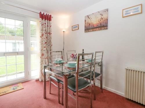 a dining room with a glass table and chairs at Sycamores in Liskeard