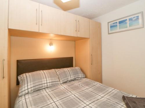 a bedroom with a bed with a checkered blanket at Sycamores in Liskeard
