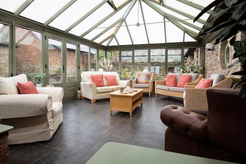 a conservatory with couches and chairs in a room with windows at East Lodge, Yorkshire in Bedale