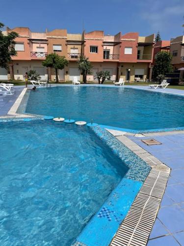 a large blue swimming pool with chairs in front of a building at Duplex a Sidi Bouzid in Sidi Bouzid