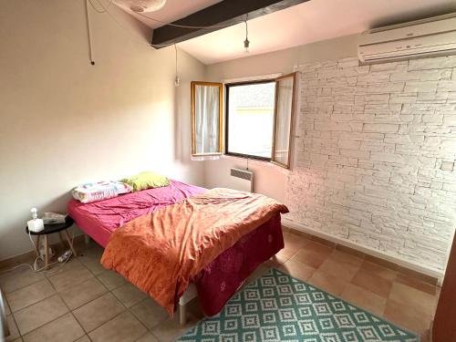 une chambre avec un lit et un mur de briques dans l'établissement La Taurelle, Maison T3 climatisée avec terrasse au cœur de Gallargues-le-Montueux, à Gallargues-le-Montueux