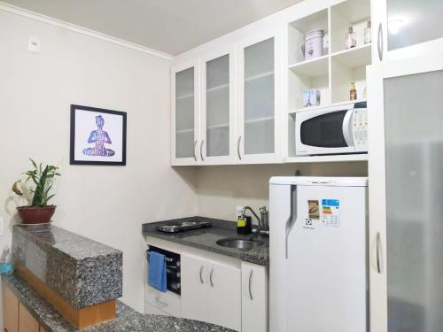 una cucina con frigorifero bianco e forno a microonde di Flat Multiparque Sudoeste a Brasilia