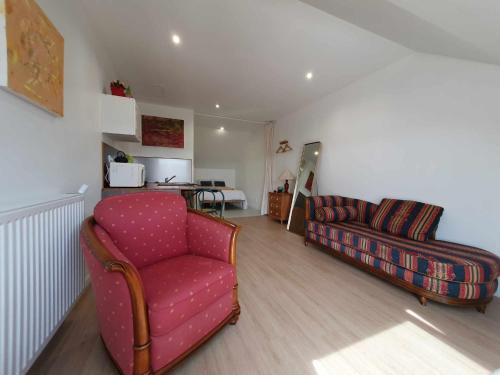 ein Wohnzimmer mit einem roten Stuhl und einem Sofa in der Unterkunft Le Duplex - La Capelette de Dany.D in Étroeungt
