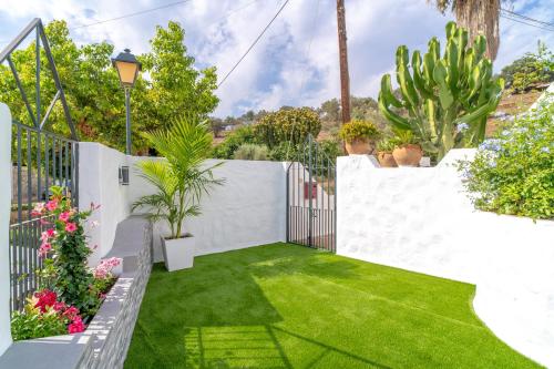 a garden with a white fence and green grass at Casa Higuera in Nerja