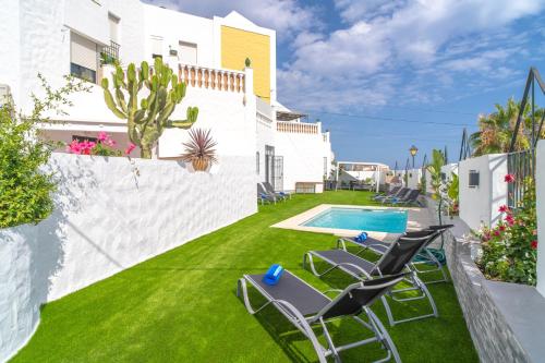 un patio trasero con sillas y una piscina en Casa Higuera, en Nerja