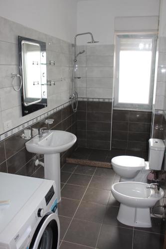 a bathroom with two sinks and a toilet and a window at COMFY CITY CENTER APARTMENT in Shkodër