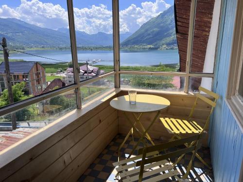 a table and chair in a balcony with a view of a lake at Hostel Bear Hug in Plav