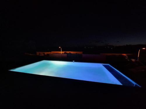 une piscine bleue éclairée la nuit dans l'établissement La Panacée, à Juvignac