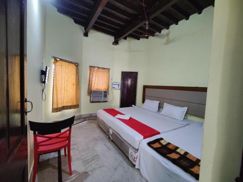 a bedroom with a large bed and a red chair at Hotel Surya Greens in Puri