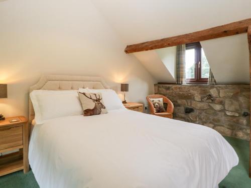 1 dormitorio con 1 cama blanca grande y pared de piedra en Redstart Cottage, en Leominster