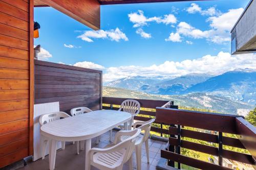 a table and chairs on a balcony with a view of mountains at Superbe appartement, en 2 parties, au centre d'Anzère in Ayent