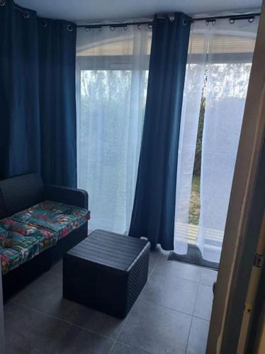 a room with a bed and a window with blue curtains at Logement plage in Saint-Cyprien