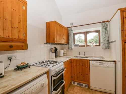 a kitchen with wooden cabinets and a stove top oven at Fieldfare in Leominster