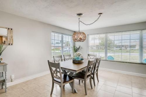 a dining room with a table and chairs and windows at Cresting Wave Cottage by the Sea in Ormond Beach