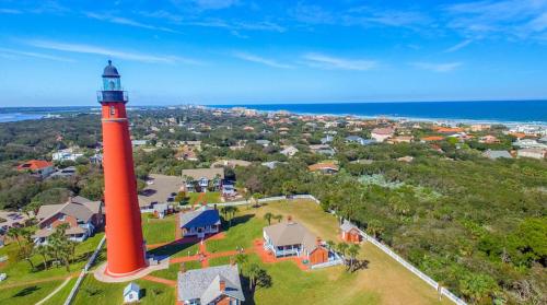 an aerial view of a red lighthouse in front of a house at Cresting Wave Cottage by the Sea in Ormond Beach