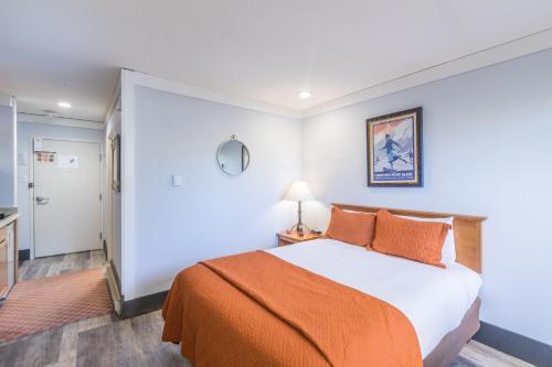 een slaapkamer met een bed met een oranje deken bij Mountainside Inn 103 Hotel Room in Telluride