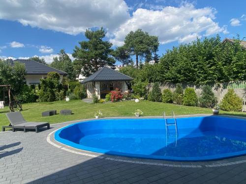 a blue swimming pool in a yard with a gazebo at Amonit in Olsztyn