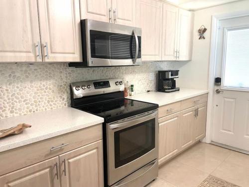 una cocina con estufa y microondas en Manatee Manor Beachfront Retreat, en Daytona Beach