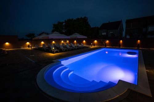 a swimming pool lit up at night at Villa Biser Dunava in Vukovar