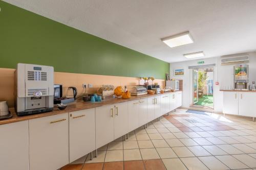 una cocina con armarios blancos y una pared verde en Résidence Les Cordeliers, en Aviñón