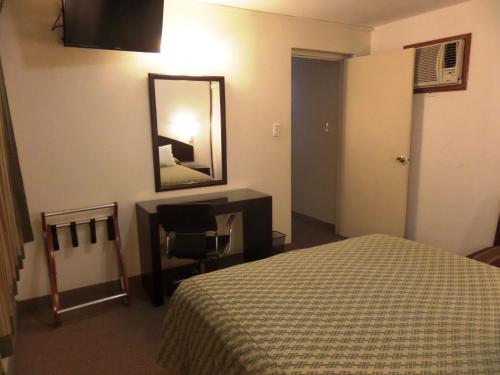 a hotel room with a bed and a desk and a mirror at Intiotel Chiclayo in Chiclayo