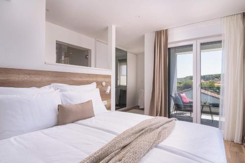 a bedroom with a white bed and a balcony at Stunning Wind Rose with 50m2 heated pool, Sauna, Gym in Trogir