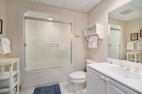 Baño blanco con aseo y lavamanos en Boyne Mountain Getaway, Unit B, en Boyne Falls