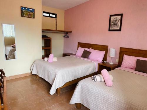 a bedroom with two beds with pink pillows at Hotel Tres Flores in Huasca de Ocampo