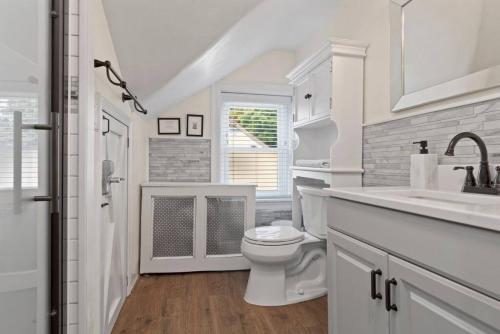 a white bathroom with a toilet and a sink at 5 Star Penthouse King Deck AC Train 