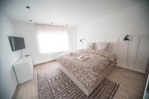 een witte slaapkamer met een bed en een televisie bij Appartement avec jardin in Pacy-sur-Eure