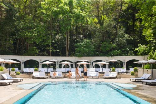 a group of people walking around a pool at a hotel at Palácio Tangará, Oetker Hotels in Sao Paulo