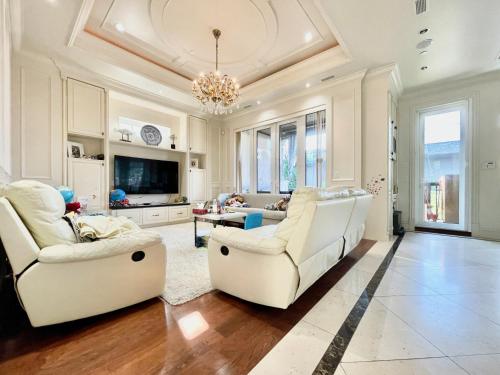 a living room with two white chairs and a tv at Vancouver Airport guesthouse in Vancouver