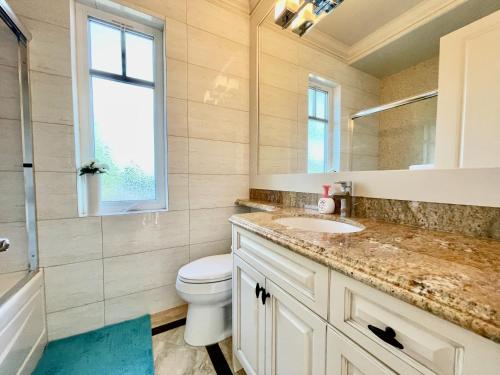 a bathroom with a sink and a toilet and a window at Vancouver Airport guesthouse in Vancouver