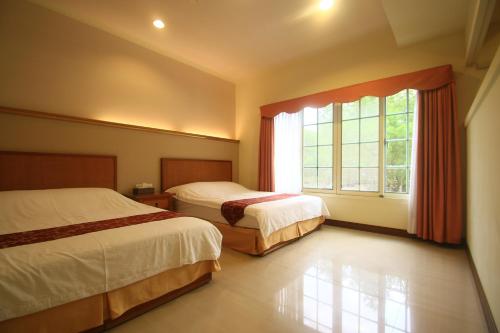 een slaapkamer met 2 bedden en een groot raam bij Malia Homestay in Hualien