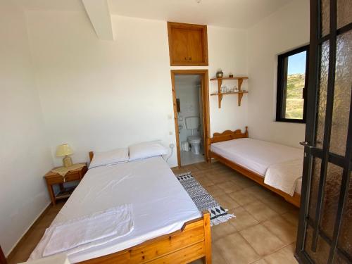a bedroom with two beds and a door to a bathroom at Coastal Charm - Sea View Room in Elíka