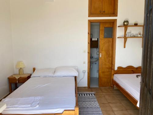a bedroom with two beds and a door to a bathroom at Coastal Charm - Sea View Room in Elíka