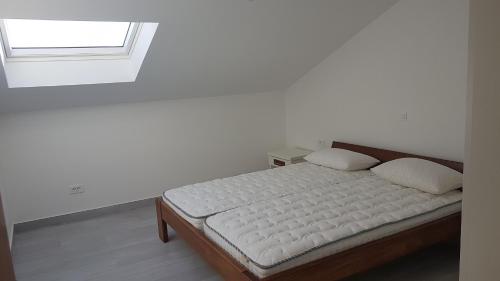 łóżko w białym pokoju z oknem w obiekcie Apartments Ivanica w Rabie