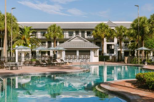 a swimming pool in front of a building with palm trees at Sonder Cirrus in Orlando