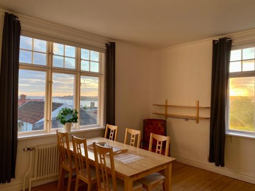 a dining room with a table and chairs and windows at Lägenhet med havsutsikt in Strömstad