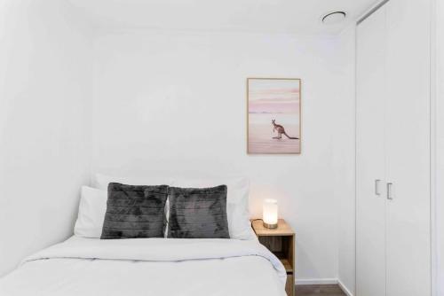 a white bedroom with a bed and a dog on the beach at Cozy Two Bedroom with Seaview - Wifi - Gym in Auckland