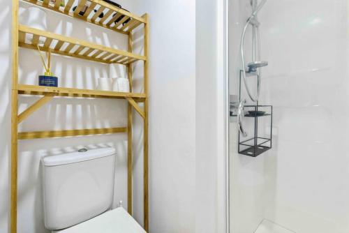a bathroom with a toilet and a wooden shelf at Cozy Two Bedroom with Seaview - Wifi - Gym in Auckland