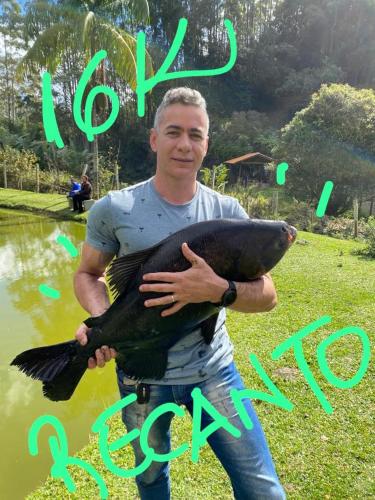 a man holding a fish in front of a pond at Chales em Salesopolis - Recanto da Barra in Salesópolis