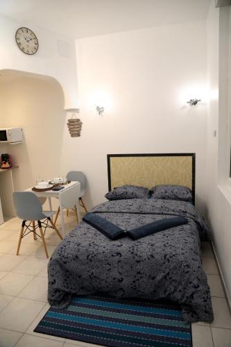 - une chambre avec un lit, une table et une horloge dans l'établissement PLUTON, à Saint-Quentin