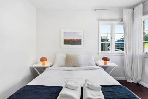 a white bedroom with a large bed with two windows at Renovated Character Central Home - WiFi & Netflix in Auckland