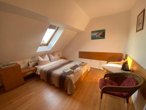 a bedroom with a bed and a chair and a window at Dom Gościnny Relax in Rewal