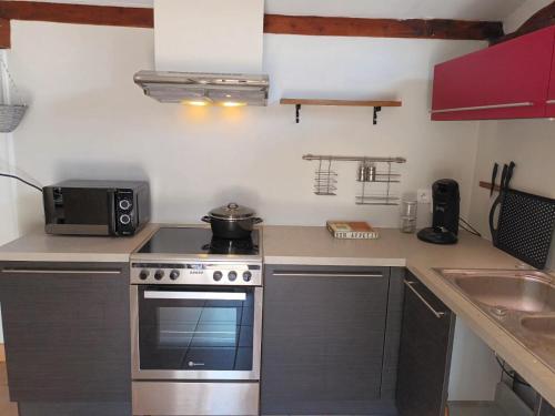 une cuisine avec une cuisinière et un micro-ondes dans l'établissement Le Cabanon, à Maussane-les-Alpilles