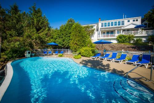 a swimming pool with blue chairs and umbrellas at Island View Inn in Glen Cove