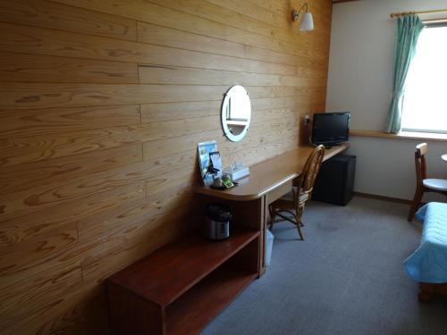 a room with a wooden wall with a desk and a mirror at Mantenbo in Hachijo